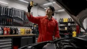Mechanic holding new oil filter by car engine