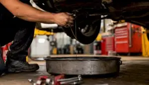 Hands draining oil from car engine