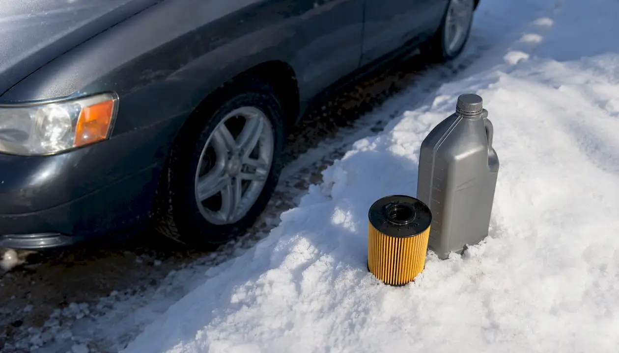 Car parked in winter with oil change supplies nearby