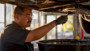 Technician draining engine oil during oil change