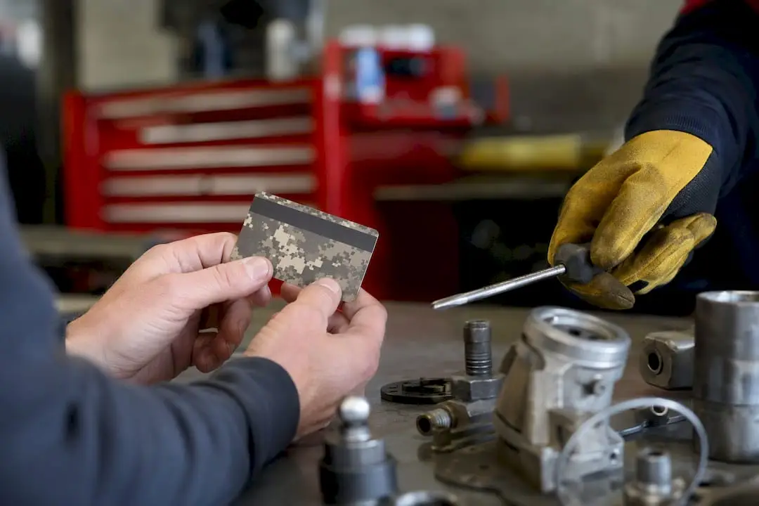 Hands holding military discount card near auto tools