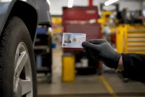 Gloved hand showing military ID near oil change station