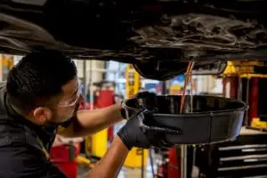 Technician draining transmission fluid in service bay