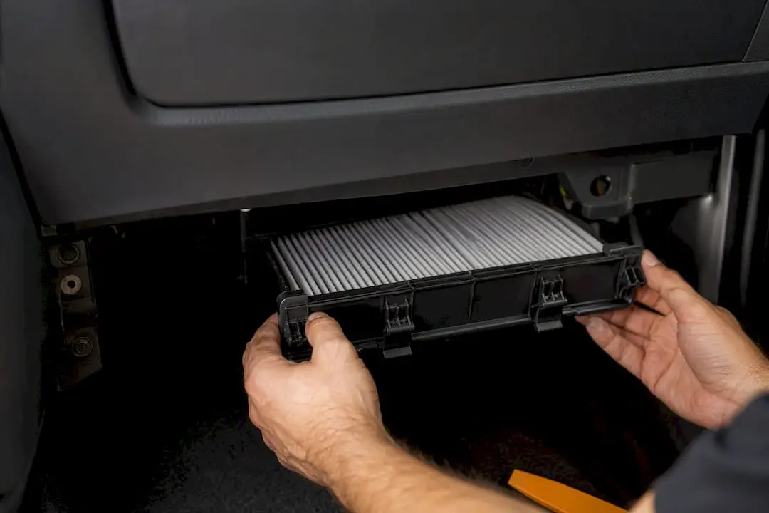 Hands accessing a cabin air filter housing