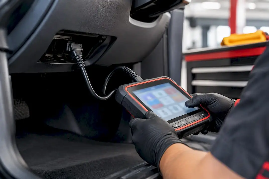 Technician scanning vehicle diagnostic port after repair